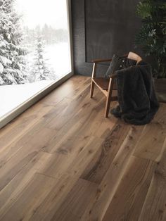 a chair sitting in front of a window on top of a wooden floor next to a tree