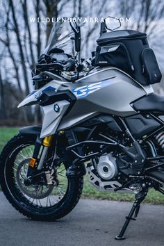 the motorcycle is parked on the side of the road in front of some grass and trees