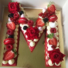 a heart shaped cake with strawberries and roses on the letter m is decorated in chocolate