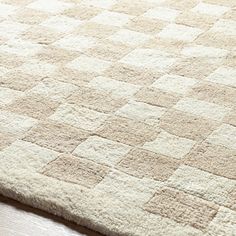 a white rug with squares on it sitting on a wooden floor in front of a window