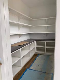 an empty room with white shelves and blue tape on the floor