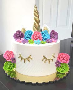 a cake decorated with flowers and a unicorn's horn