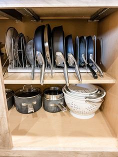 an open cabinet filled with pots and pans