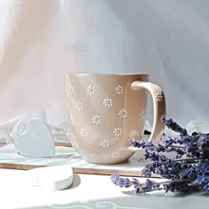 a coffee cup sitting on top of a table next to some lavenders and other items