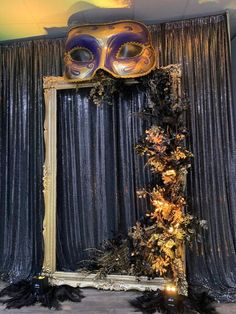 a mirror with a mask on top of it next to a black and gold curtain