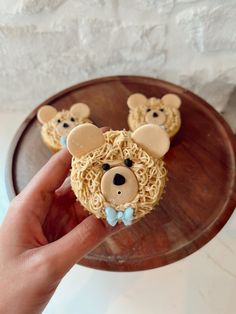 a person holding up some cupcakes with mice on them in front of a wooden tray