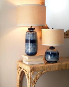 two blue vases sitting on top of a table next to a lamp and mirror