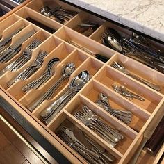 an open drawer filled with silverware and utensils on top of a counter