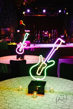 a guitar shaped neon sign sitting on top of a table