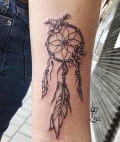 a woman's arm with a tattoo on it that looks like a dream catcher