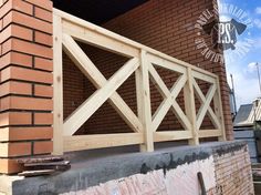 a brick building with a wooden gate on the front and side of it that is being built