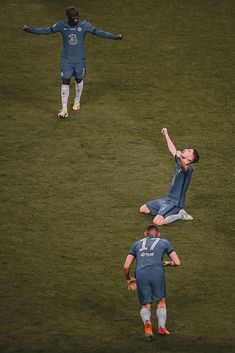 two soccer players in blue uniforms are on the field and one is reaching up to catch the ball