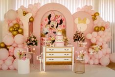 a pink and gold minnie mouse birthday party with balloons, cake and decorations on the table