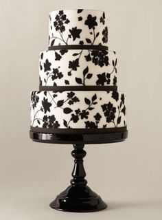 a three tiered cake with black and white flowers on it's icing