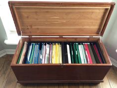 an open wooden box filled with lots of different colored papers