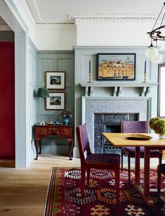 the dining room is decorated in shades of blue and red, with an ornate fireplace