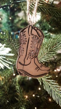 a christmas ornament hanging from a tree with lights in the background and an image of a cowboy boot on it