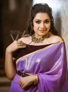 a woman in a purple sari posing for the camera with her hands on her hips