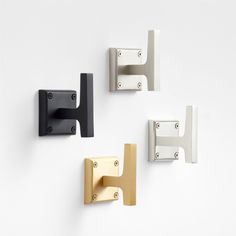 three white and black wall mounted brackets on the side of a wall next to each other