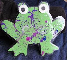 a green frog with eyes and paint splattered on it