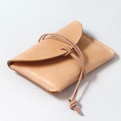 a tan leather pouch with a knot tied around the outside of it on a white surface