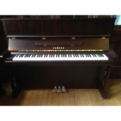 a piano sitting on top of a wooden floor next to a pair of white shoes