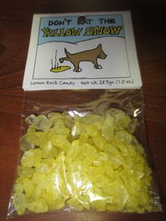 a bag of yellow gummy bears sitting on top of a wooden table next to a sign