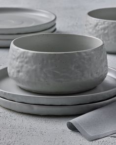 three white dishes sitting on top of each other next to silver plates and napkins