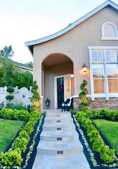 a house with steps leading up to the front door and landscaping in front of it