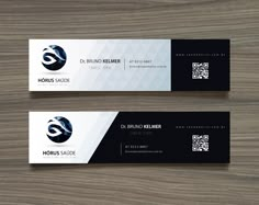 two black and white business cards sitting on top of a wooden table