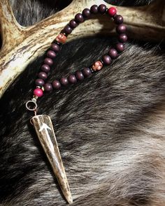 a necklace with a long horn on it's end and beads around the neck