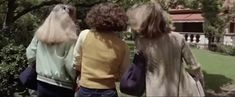 three women are walking in the park together and one is wearing a long white wig