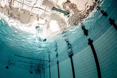 an underwater view of a swimming pool with blue water and white tiles on the walls