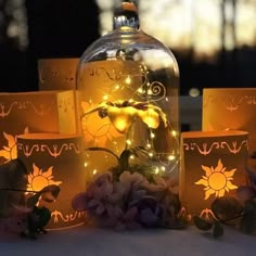 a bottle with some lights in it sitting on a table next to flowers and candles