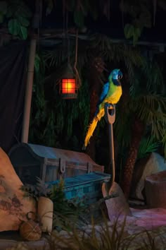 a blue and yellow parrot sitting on top of a wooden pole in front of trees