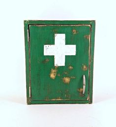 an old green medicine cabinet with a white cross on the front and bottom panel, against a white background