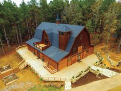 an aerial view of a large wooden house in the middle of a forest with lots of trees