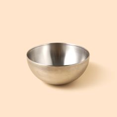 a metal bowl sitting on top of a beige surface with no one in it's place