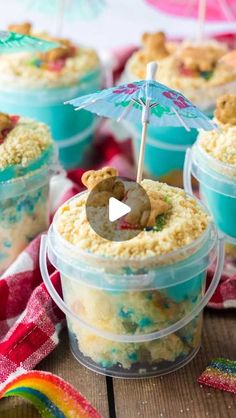 some food in small plastic containers on a wooden table with an umbrella and rainbow streamers