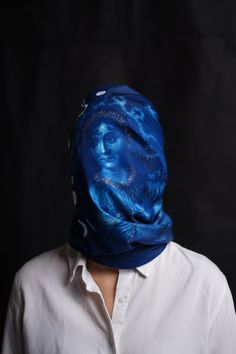 a person wearing a blue scarf over their head with the image of a man's face on it