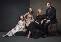 a family posing for a portrait in formal wear and dress clothes, sitting on a chair