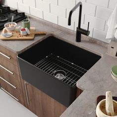 a black sink in a kitchen next to a cutting board and wooden utensils