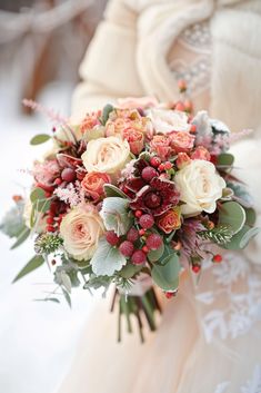 a bridal holding a bouquet of flowers and greenery on her wedding day in the snow