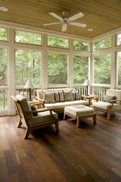 a living room filled with lots of furniture on top of a hard wood floor covered in windows