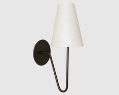 a wall light with a white shade on it's side and a black arm