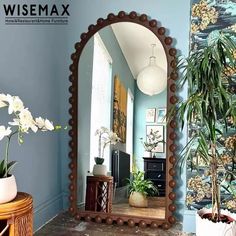 a mirror sitting on top of a wooden table next to a potted palm tree