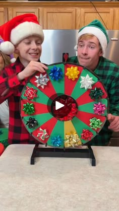 two people in christmas hats holding up a spinning wheel