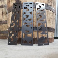 three metal signs sitting next to each other on top of a wooden barrel filled with barrels