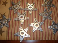 several metal ornaments are arranged on a striped tablecloth with stars in the background and one has an ornament that looks like a snowflaker