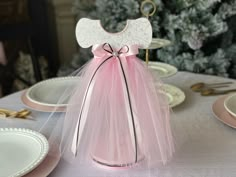 a table with plates, silverware and pink tulle dress on top of it